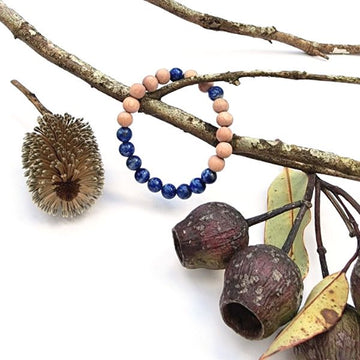 Handmade Intuition Bracelet – Lapis Lazuli & Rosewood for Intuition & Wellbeing on white table laid on a branch with gum nuts